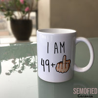 I am 49 + Middle Finger Mug - 50th Birthday Cup on Glass Table